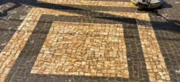 Piso de pedra portuguesa com o desenho encoberto por sujeira, durante a passagem da rotativa.